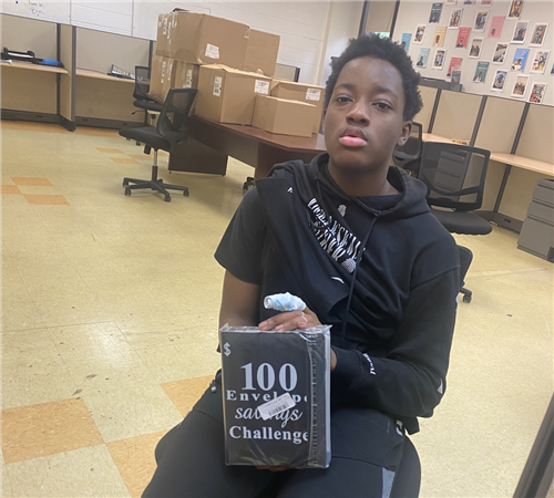 single student holding up a black savings challenge binder